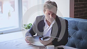 Handsome businessman looking at magazin sitting at the table