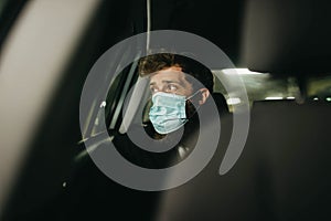 Handsome businessman in medical mask using mobile phone in car, concept of coronavirus quarantine