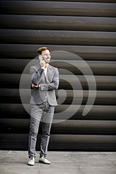 Handsome businessman with mobile phone by office building
