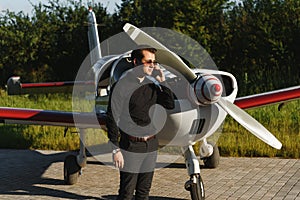 Handsome businessman near private jet. Successful man at the airport talking on the phone