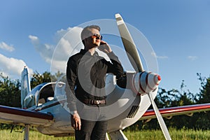 Handsome businessman near private jet. Successful man at the airport talking on the phone