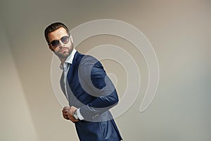 Handsome businessman at office. Bearded man in a stylish suit and sunglasses is standing at office and looking away