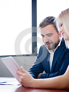 Handsome businessman and office woman working with tablet on a blurred background. Office meeting concept.