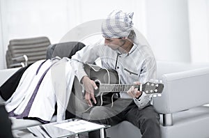 Handsome businessman playing the guitar in office