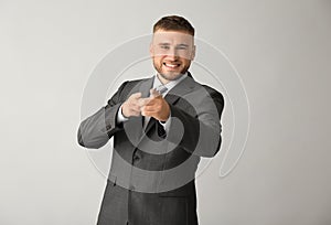 Handsome businessman pointing at viewer on grey background