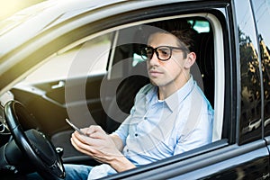 Handsome businessman sending a text message in his car