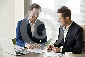 Handsome businessman signing contract with partner