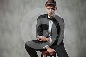 Handsome businessman sitting on chair fixes his tuxedo sleeve