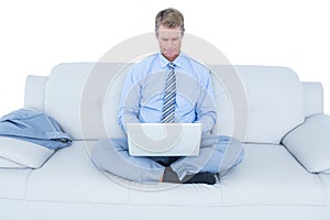 Handsome businessman sitting on sofa using his laptop