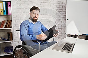 Handsome businessman sitting in a wheelchair and holding a clipboard