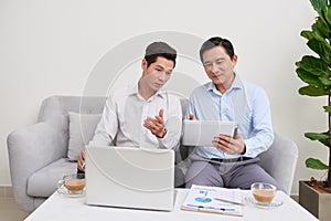 Handsome businessman smiling while working with a laptop at home