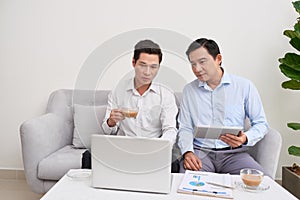 Handsome businessman smiling while working with a laptop at home