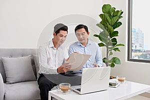 Handsome businessman smiling while working with a laptop at home