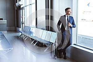 handsome businessman standing at departure lounge and looking at window