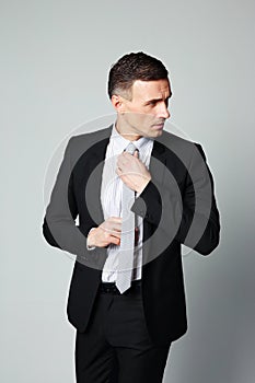 Handsome businessman straightening his tie