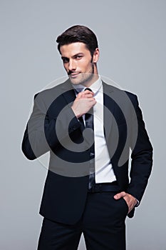 Handsome businessman straightening his tie