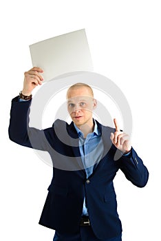 Handsome businessman in stylish suit holding empty sheet of paper over his head isolated on white background