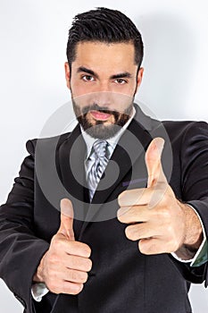 Handsome businessman in suit giving thumbs up with expression of confidence.