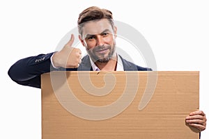 Handsome businessman in suit holding empty board on studio background. Business man with thumb up showing blank