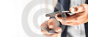 Handsome businessman in suit holding a smart phone in hand and paying by a credit card in local shop