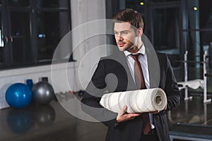 handsome businessman in suit holding yoga mat