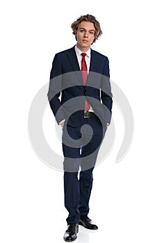 Handsome businessman in suit posing with hands in pockets