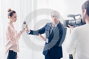 Handsome businessman in suit rejecting giving video interview to journalist and gesturing