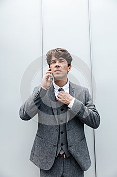 Handsome businessman in suit standing and talking on mobile phone