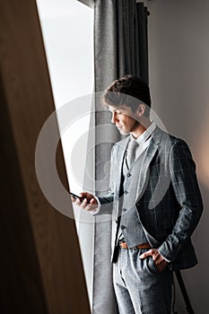 Handsome businessman in suit standing and typing message