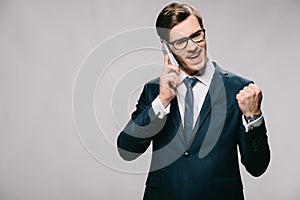 Handsome businessman talking on smartphone and celebrating victory isolated