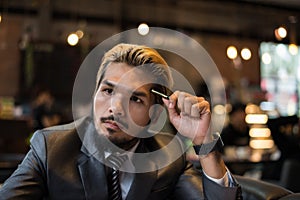 Handsome businessman thinking about work while working at cafe.