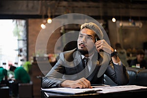 Handsome businessman thinking about work while working at cafe.