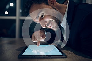 Businessman working with tablet late at night.