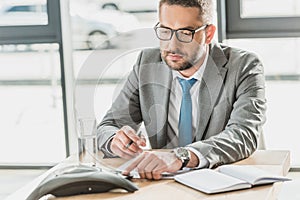 handsome businessman using conference phone on table