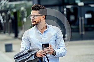 Handsome businessman using mobile phone app outside of office. Successful man holding smartphone for business work