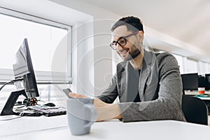 Handsome businessman is using a smartphone and smiling while working in office