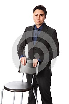 Handsome businessperson in suit leaning against a chair