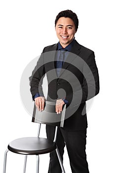 Handsome businessperson in suit leaning against a chair