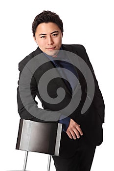 Handsome businessperson in suit leaning against a chair