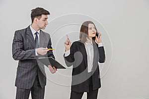 Handsome busy businesswoman is talking on the phone, pointing his finger up for her secretary to wait. Male secretary photo