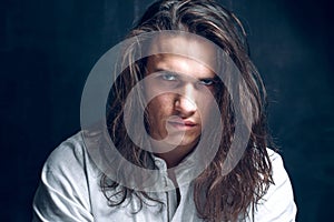 Handsome calm man. Strong boy on an isolated dark background in the studio