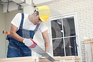 A handsome carpenter is cutting wood