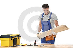 Handsome carpenter working with timber at table on white background