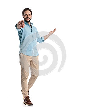 handsome casual man pointing finger forward while walking and inviting to side