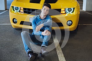 Handsome casual man sitting near the modern yellow sport car. Fashion. Modern. Advertising