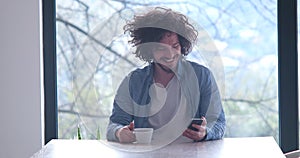 Young man drinking coffee and using a mobile phone at home