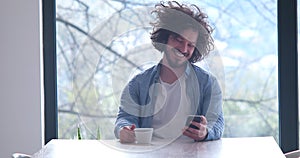 Young man drinking coffee and using a mobile phone at home