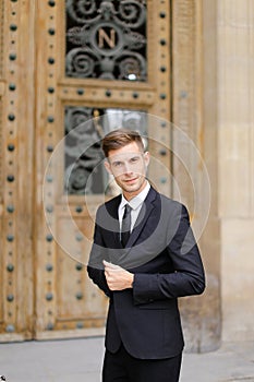 Handsome cauasian groom standing near wooden door. photo