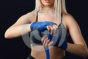 Handsome caucasian blonde woman wrapping her hands with a band for boxing