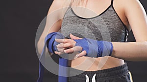Handsome caucasian blonde woman wrapping her hands with wraps for boxing